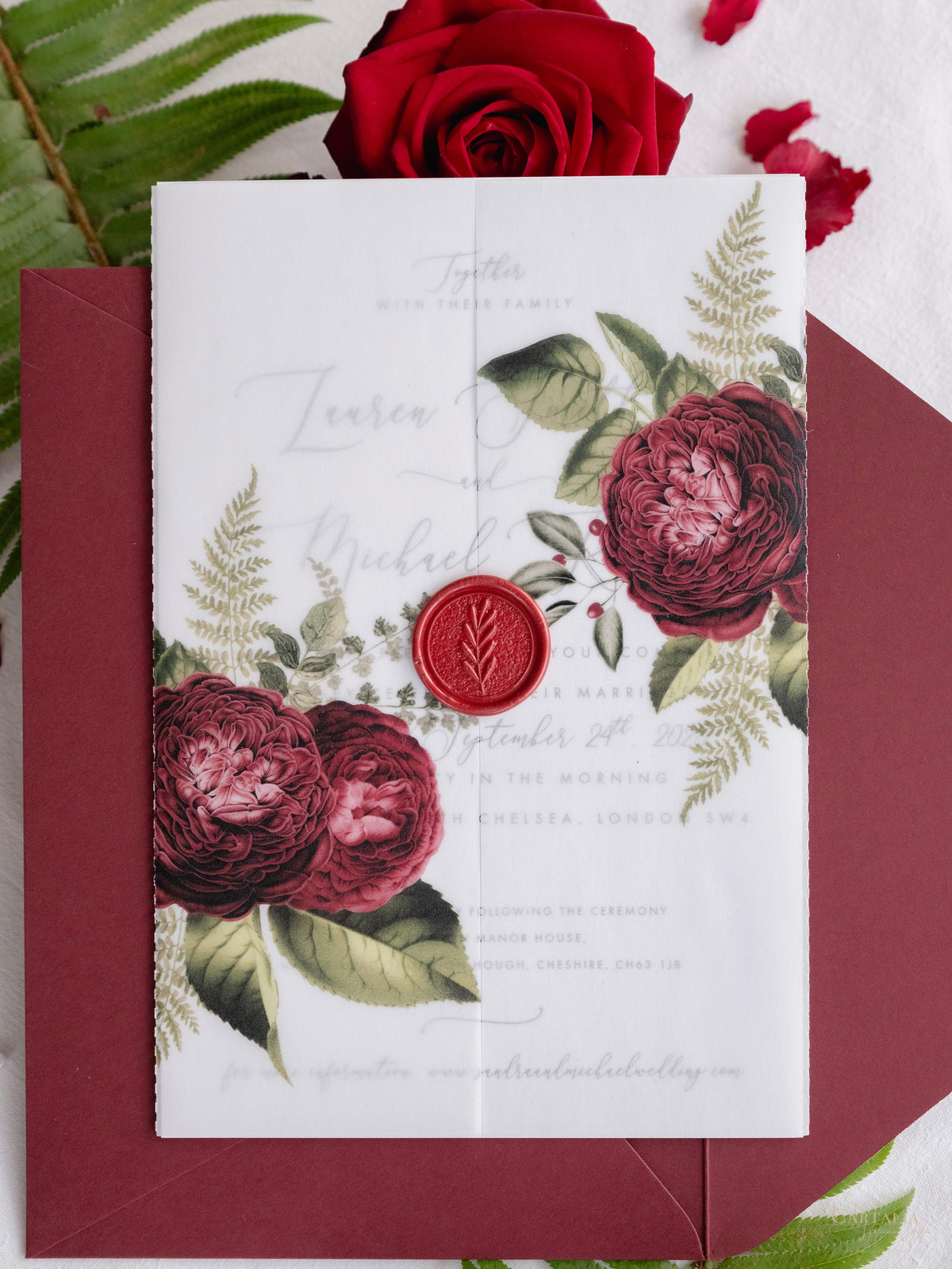 Invitación con manga de pergamino de caligrafía moderna con detalles florales de color rojo intenso y sello de cera de Burdeos