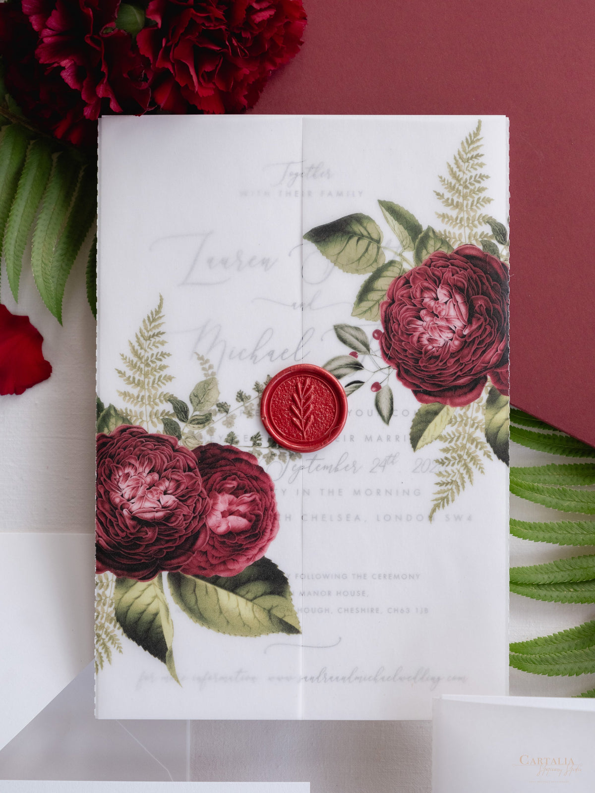 Invitación con manga de pergamino de caligrafía moderna con detalles florales de color rojo intenso y sello de cera de Burdeos