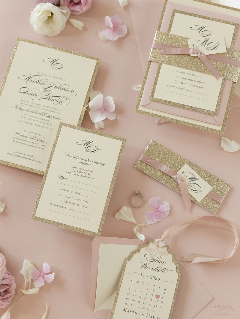 Suite di invito a strati con glitter dorati con etichetta monogramma e nastro con fascia per la pancia