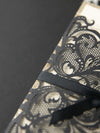 Elegante apertura laser Black Opulence con design a nastro e glitter dorati.