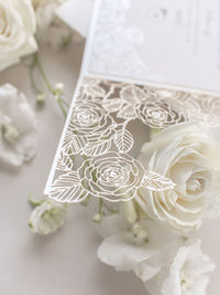 Détail de roses coupées au laser complexe avec une invitation du jour du mariage de style nombril du ventre de papier perlé