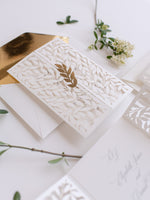Classica apertura ad arco in avorio con intricata foglia tagliata al laser e invito per il giorno in pizzo lamina d'oro