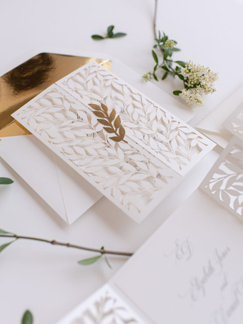 Classica apertura ad arco in avorio con intricata foglia tagliata al laser e invito per il giorno in pizzo lamina d'oro